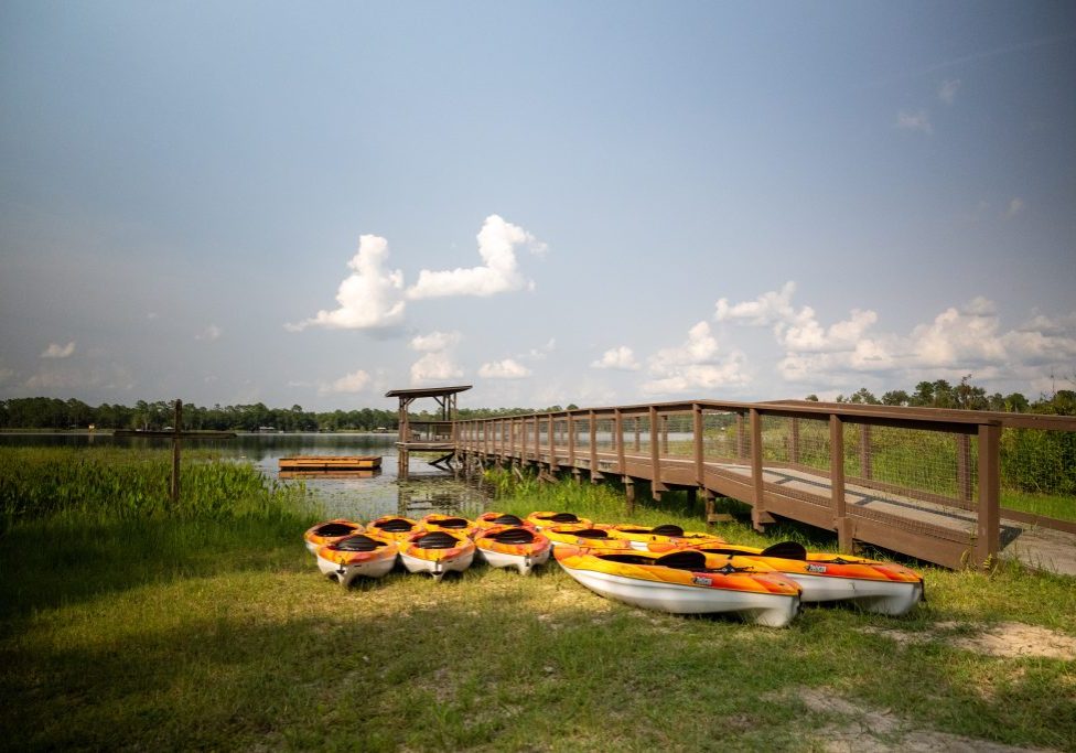 Kayaks lined up on the grass beside the dock and boardwalk at Luther Springs