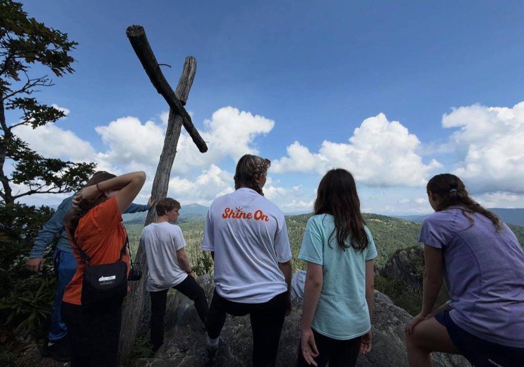 Campers on the rock beside the wooden cross at Lutherock, looking out over the mountains